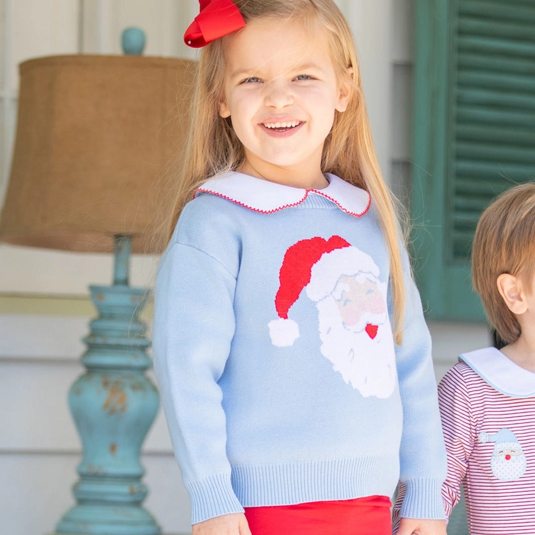 Girl in a blue Santa sweater next to a boy, matching outerwear