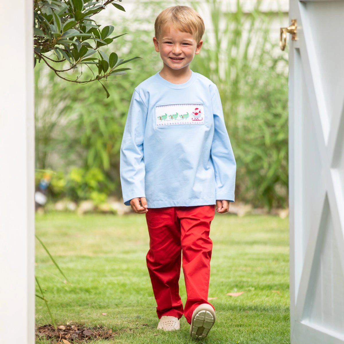 Boy in a light blue smocked shirt and red pants
